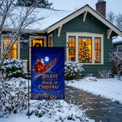 Believe in the Magic of Christmas garden flag outside a green bungalow with a lit tree
