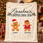 Grandma's Christmas Cookie Crew personalized blanket with 2 grandkids' names, held up in a Christmas living room