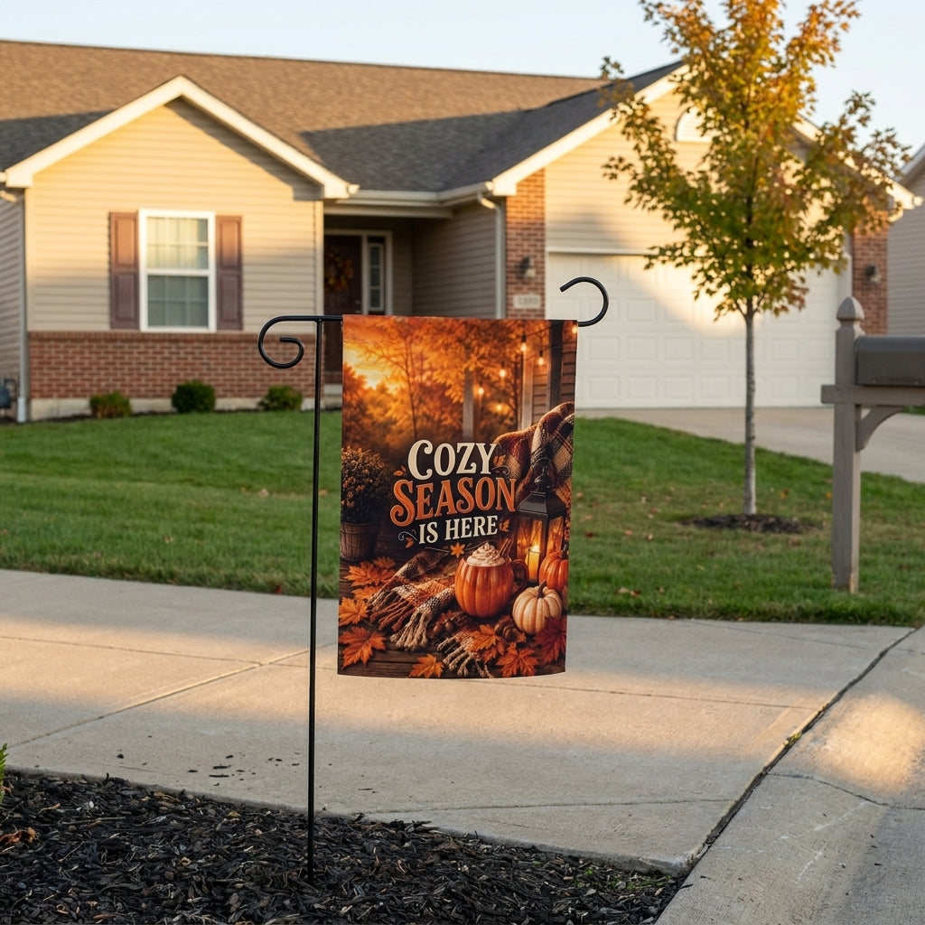 Cozy Season Is Here garden flag on a stand outside a tan ranch home