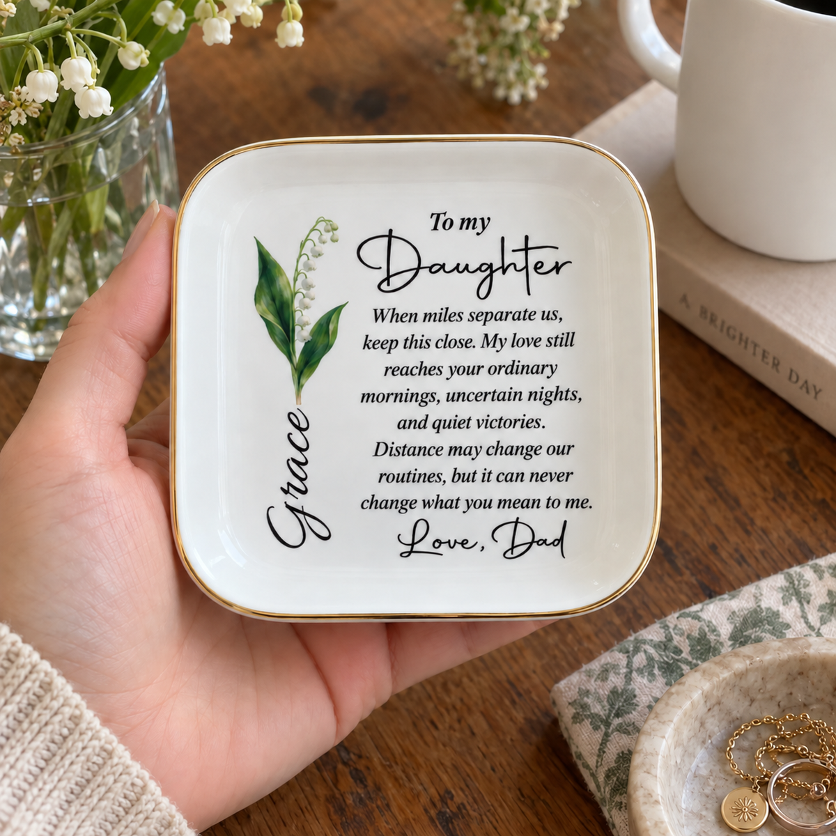 Hand holding personalized To My Daughter long distance jewelry dish with birth flower and name